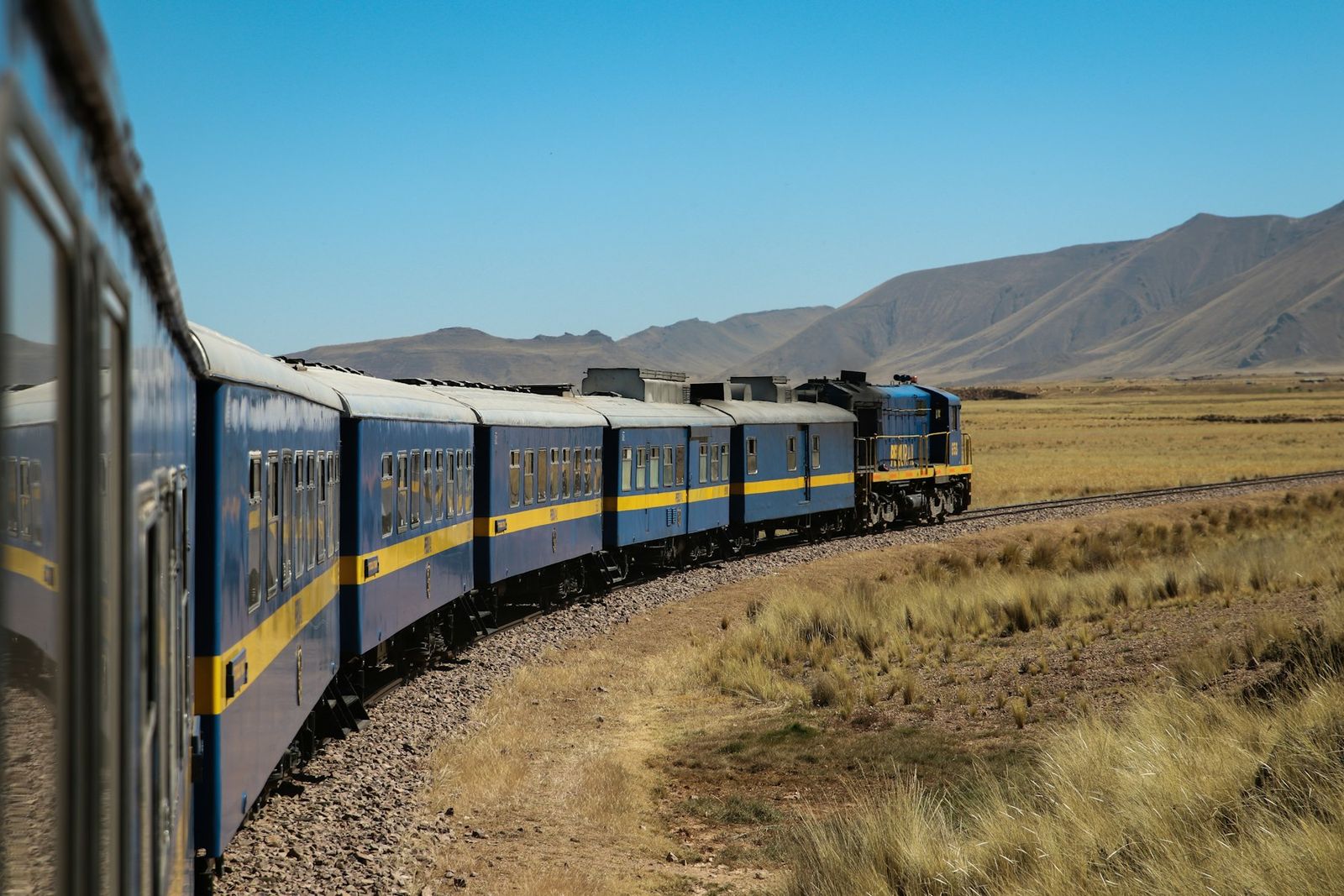 Tren panoramic albastru oprit într-o gară din Valea Urubamba