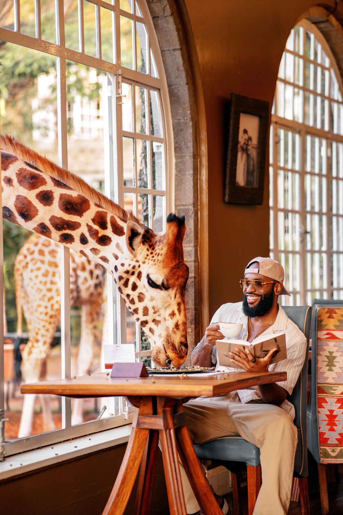 Mic dejun la Giraffe Manor din Nairobi, cu o girafă care intră pe fereastră lângă un oaspete